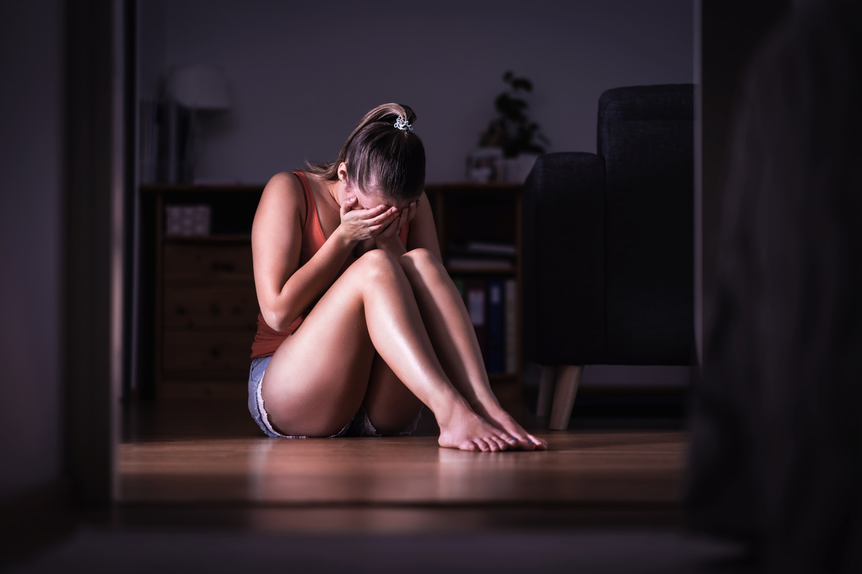 A person sitting on the floor with her hands in her face

Description automatically generated